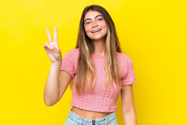 Young caucasian woman isolated on yellow background smiling and showing victory sign