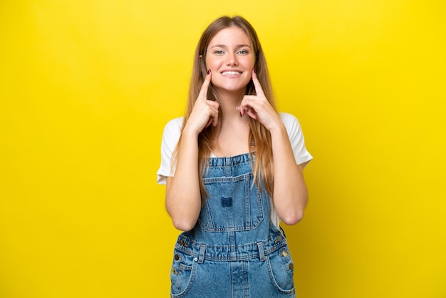 Young caucasian woman isolated on yellow background smiling with a happy and pleasant expression