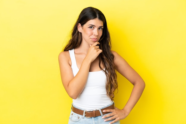 Young caucasian woman isolated on yellow background thinking