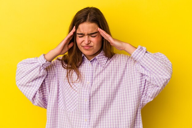 Young caucasian woman isolated on yellow background touching temples and having headache.