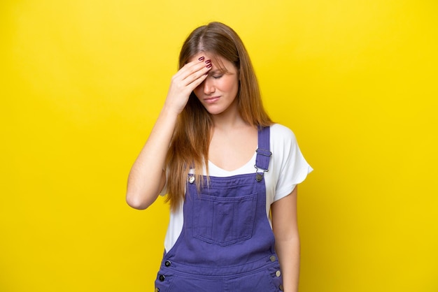 Young caucasian woman isolated on yellow background with headache