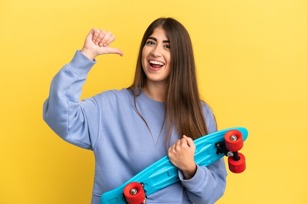 Young caucasian woman isolated on yellow background with a skate with happy expression