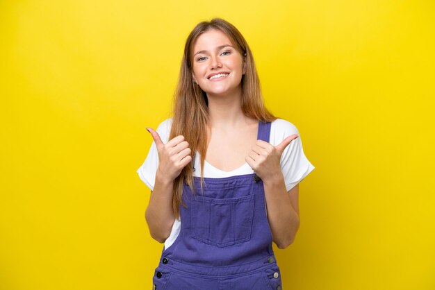 Young caucasian woman isolated on yellow background with thumbs up gesture and smiling