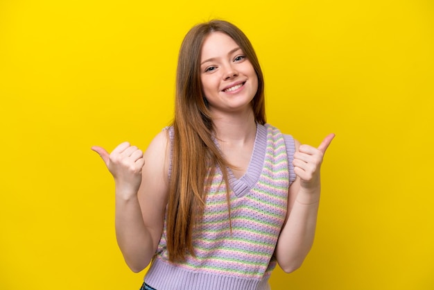 Young caucasian woman isolated on yellow background with thumbs up gesture and smiling