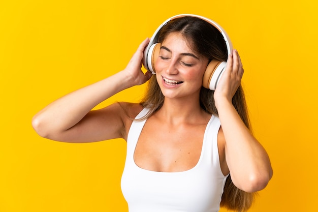 Young caucasian woman isolated on yellow listening music