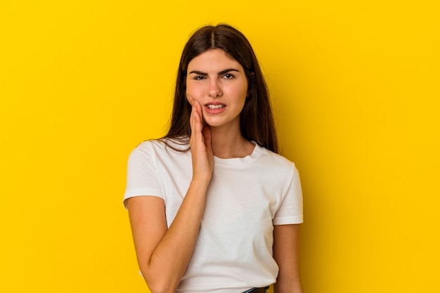 Young caucasian woman isolated on yellow wall having a strong teeth pain, molar ache.