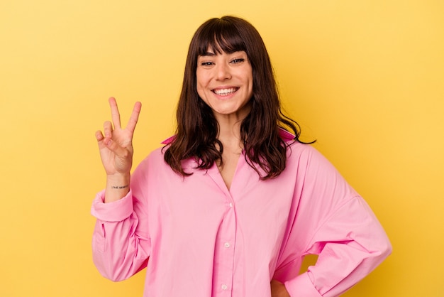 Young caucasian woman isolated on yellow wall showing number two with fingers