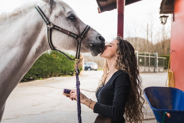 Young caucasian woman kissing a horse