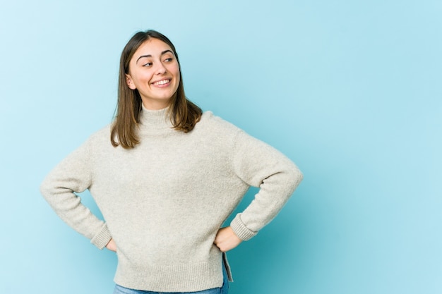 Young caucasian woman laughs happily and has fun keeping hands on stomach.