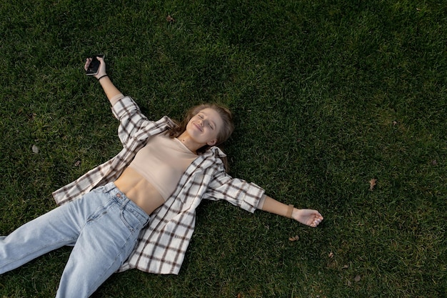 Young caucasian woman lies on green grass and smiles