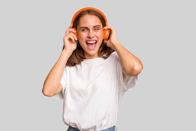 Young caucasian woman listening to music with headphones isolated