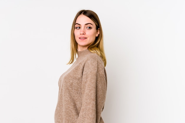 Young caucasian woman looks aside smiling, cheerful and pleasant.