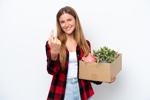 Young caucasian woman making a move while picking up a box full of things isolated on white background doing coming gesture