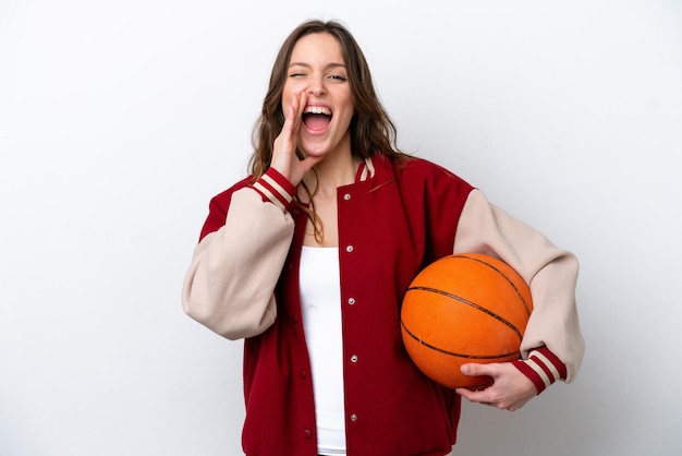 Young caucasian woman playing basketball isolated on white background shouting with mouth wide open