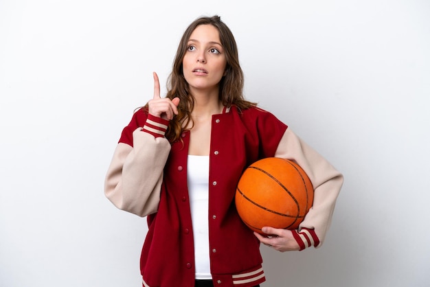 Young caucasian woman playing basketball isolated on white background thinking an idea pointing the finger up