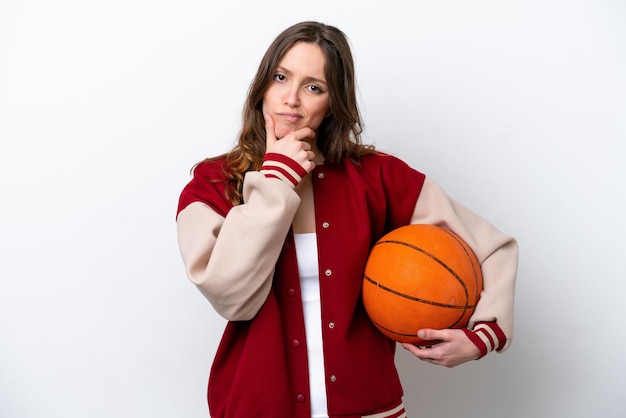 Young caucasian woman playing basketball isolated on white background thinking