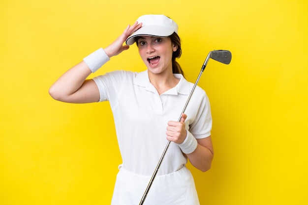 Photo young caucasian woman playing golf isolated on yellow background with surprise expression