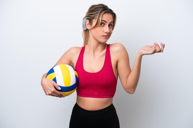 Young caucasian woman playing volleyball isolated on white background having doubts while raising hands