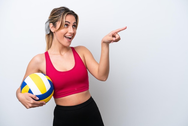 Young caucasian woman playing volleyball isolated on white background pointing finger to the side and presenting a product