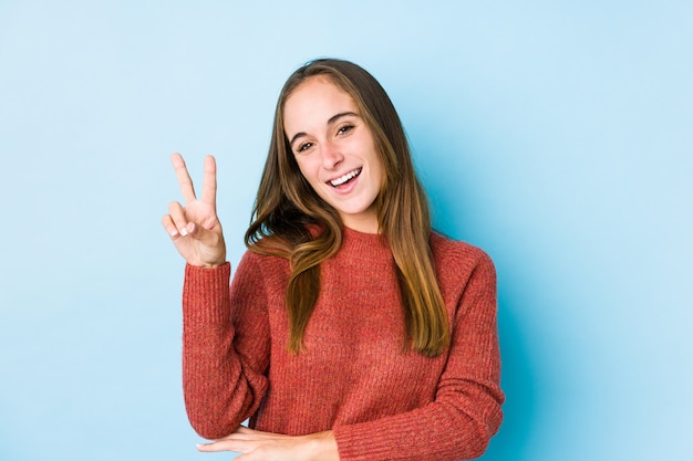 Young caucasian woman posing isolated  joyful and carefree showing a peace symbol with fingers.