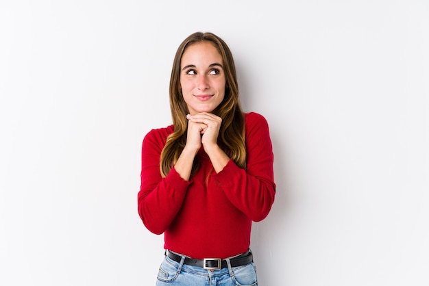 Young caucasian woman posing isolated  keeps hands under chin, is looking happily aside.