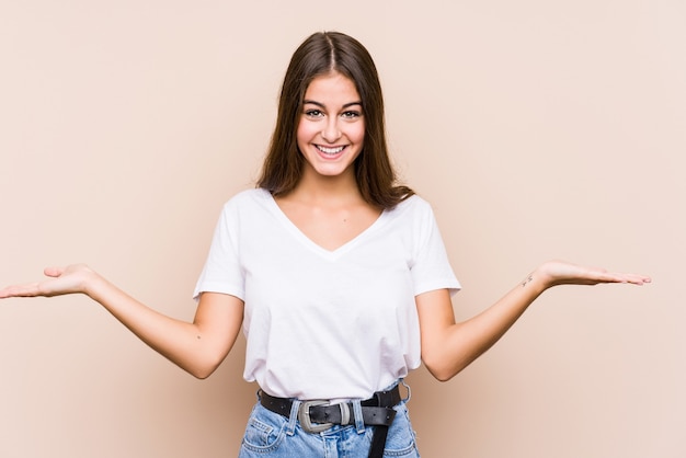 Young caucasian woman posing isolated makes scale with arms, feels happy and confident.