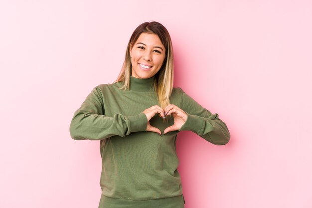 Young caucasian woman posing isolated  smiling and showing a heart shape with hands.