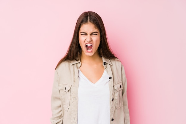 Young caucasian woman posing in a pink  screaming very angry and aggressive.