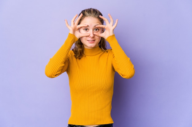 Young caucasian woman on purple keeping eyes opened to find a success opportunity.