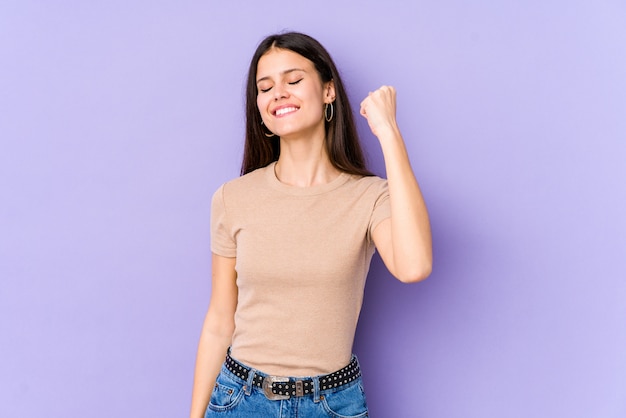 Young caucasian woman on purple wall celebrating a victory, passion and enthusiasm, happy expression.