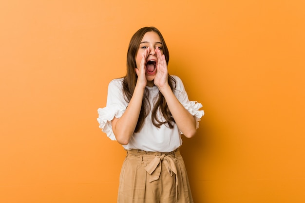 Young caucasian woman shouting excited to front.