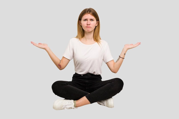 Young caucasian woman sitting on the floor cutout isolated