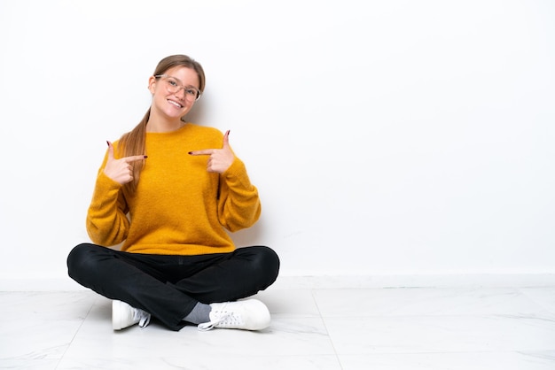 Young caucasian woman sitting on the floor isolated on white background proud and selfsatisfied