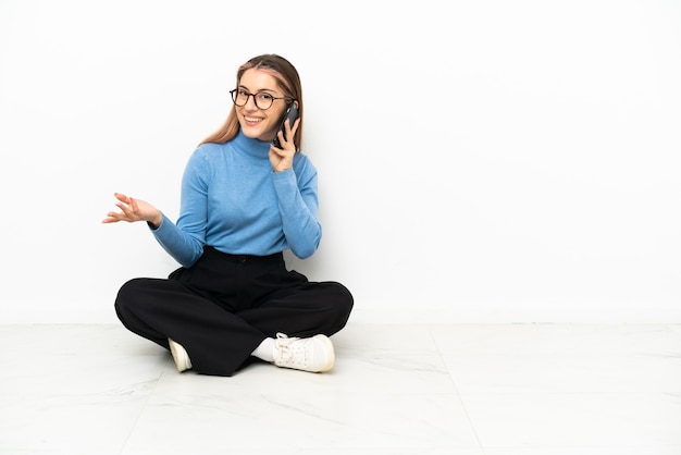 Young Caucasian woman sitting on the floor keeping a conversation