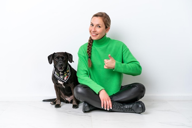 Young caucasian woman sitting on the floor with his puppy isolated on white background with thumbs up because something good has happened