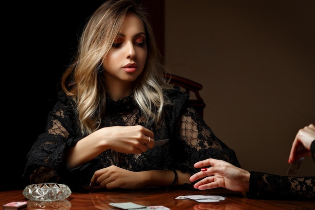 Photo young caucasian woman sitting at a table and playing cards on the strip