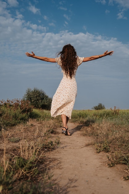 A young Caucasian woman spinning in a picturesque steppe boundless landscape Autumn or summer