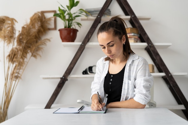 Young caucasian woman student or remote worker sitting at a desk at home in an office