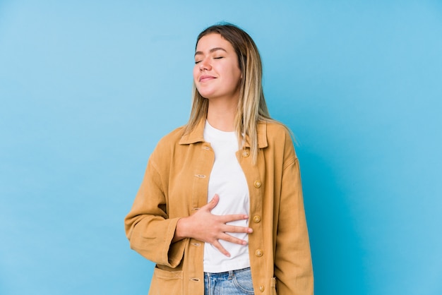 Young caucasian woman touches tummy, smiles gently, eating and satisfaction concept.