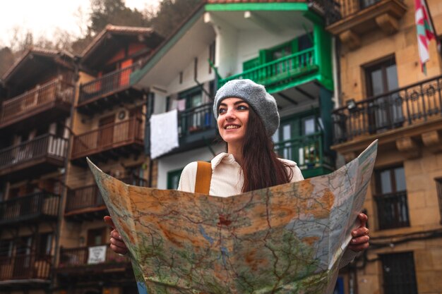 Young caucasian woman traveler looking a map and colorful facades behind