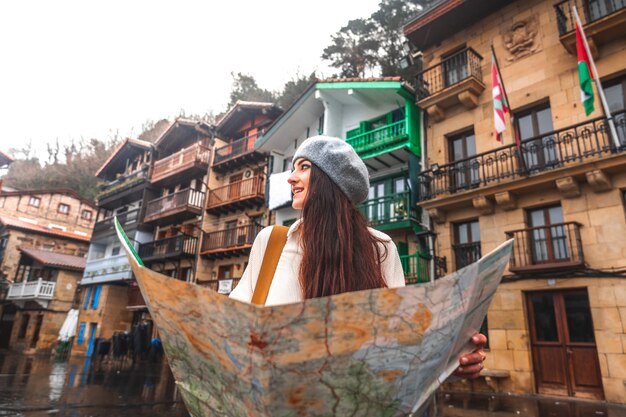 Young caucasian woman traveler looking a map and colorful facades behind