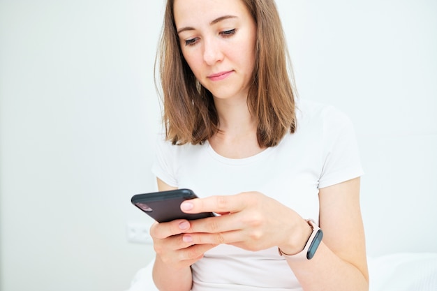 Young caucasian woman uses phone at home