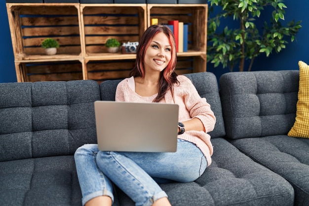 Young caucasian woman using laptop sitting on sofa at home