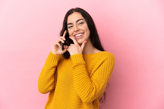 Young caucasian woman using mobile phone isolated on pink wall happy and smiling