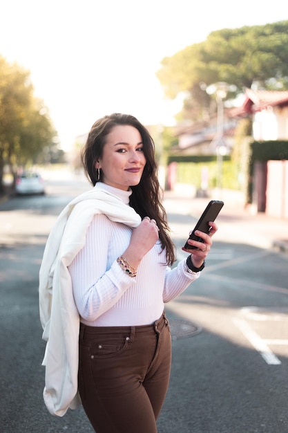 Young caucasian woman walking on the street using a smartphone