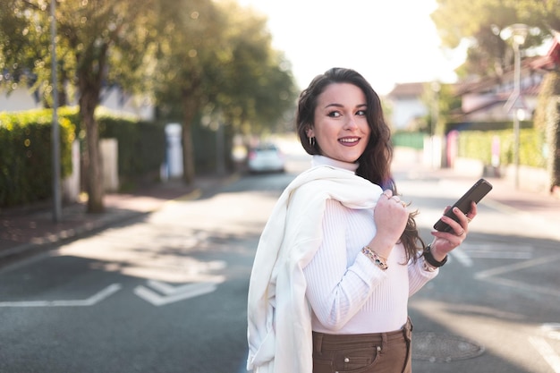 Young caucasian woman walking on the street using a smartphone