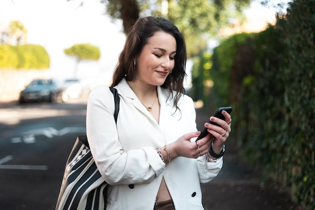 Young caucasian woman walking on the street using a smartphone