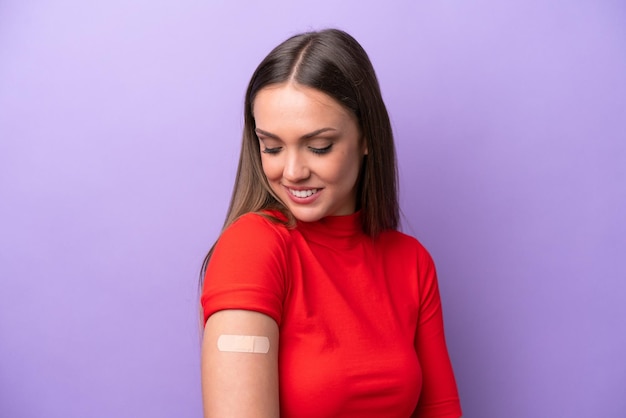 Young caucasian woman wearing band aid isolated on purple background with happy expression