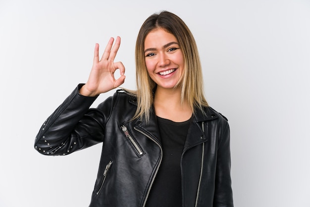 Young caucasian woman wearing a black leather jacket cheerful and confident showing ok gesture.