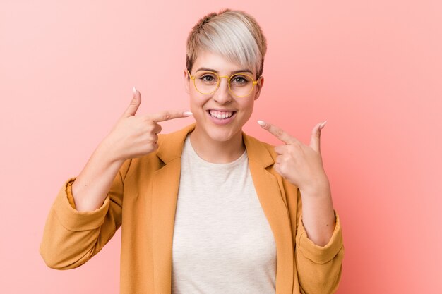 Photo young caucasian woman wearing a casual business clothes smiles, pointing fingers at mouth.